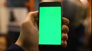 up of hand holding a smartphone with green screen display at underground train station shot