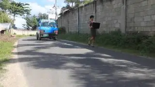 Skinny gay viewing laptop while walking on the street.