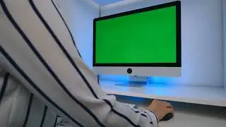 A woman wearing an elegant shirt works at the computer with a displayed green screen