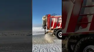 Грузовик поливает водой из бочки зимник