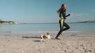 young adult athletic woman running with dog near sea rv