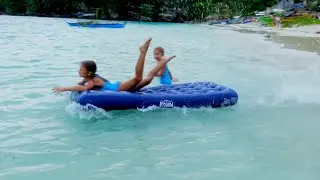 Children playing on the beach. Jumping on the mattress