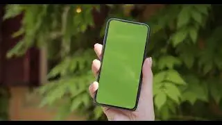 close up of black smartphone with green screen in woman hand outdoors female finger